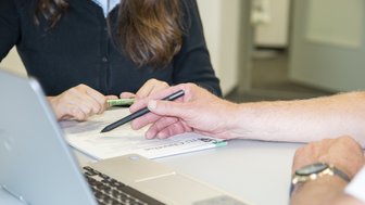 Eine Person erklärt einer anderen etwas auf einem Zettel